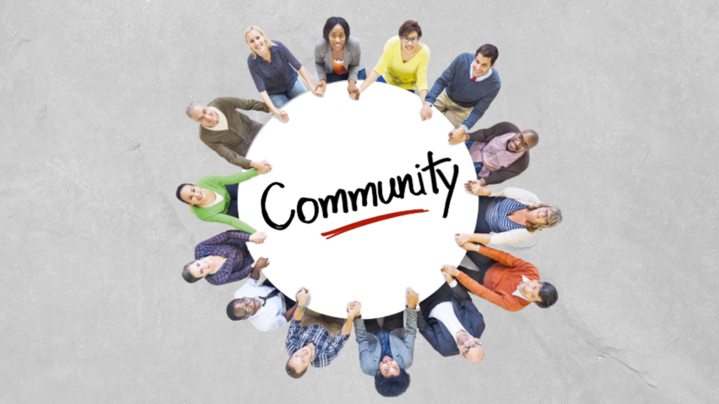 Group of diverse individuals sitting around a table that reads "Community"